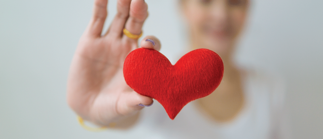 blurred woman in background holding felt heart in focus
