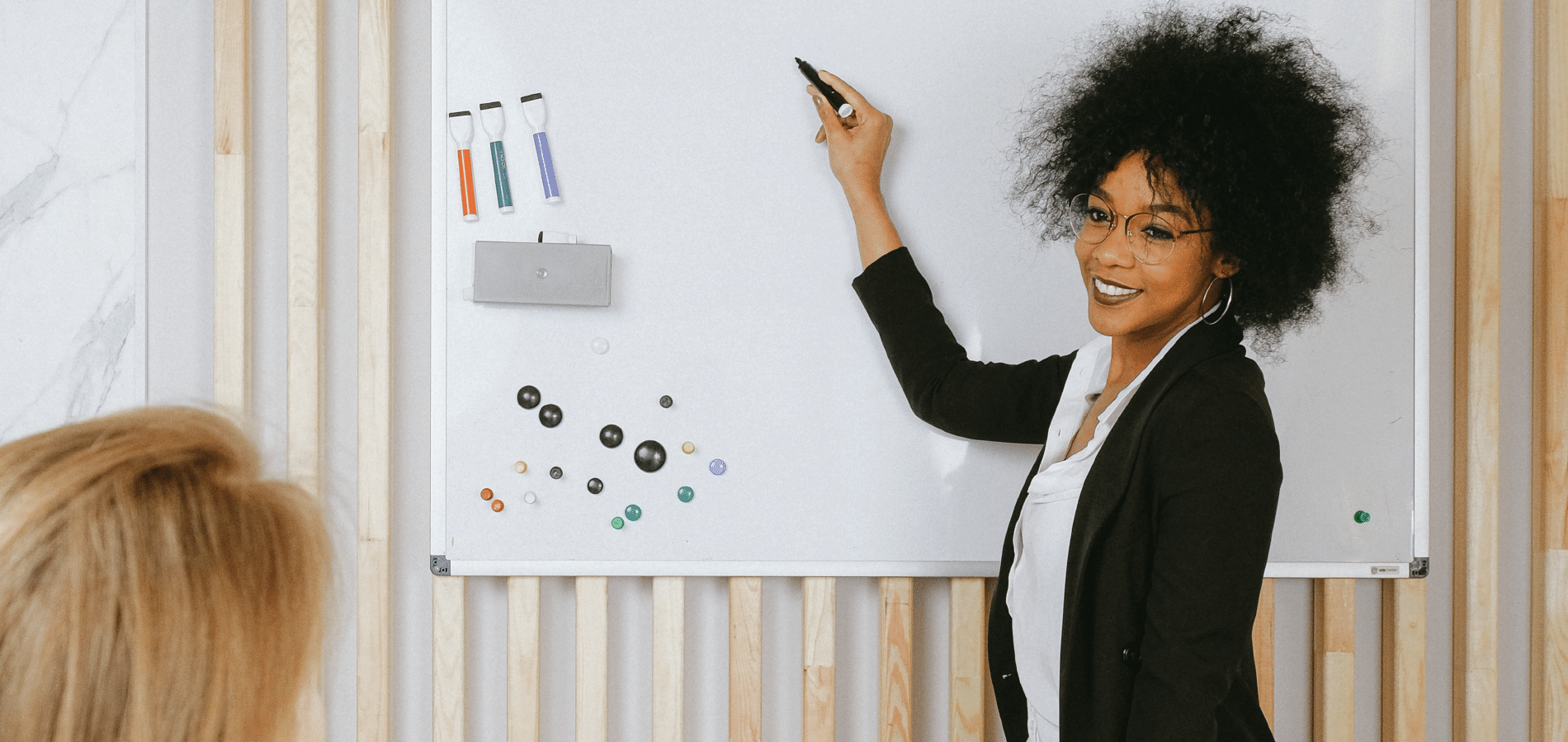 Trainer holding dry erase marker and smiling in front of white board