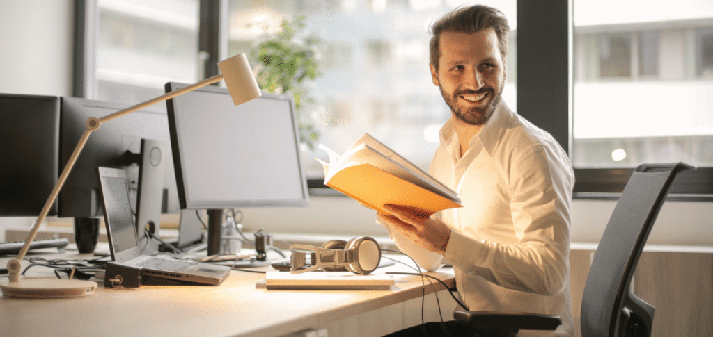 male sitting at desk in office environment smiling