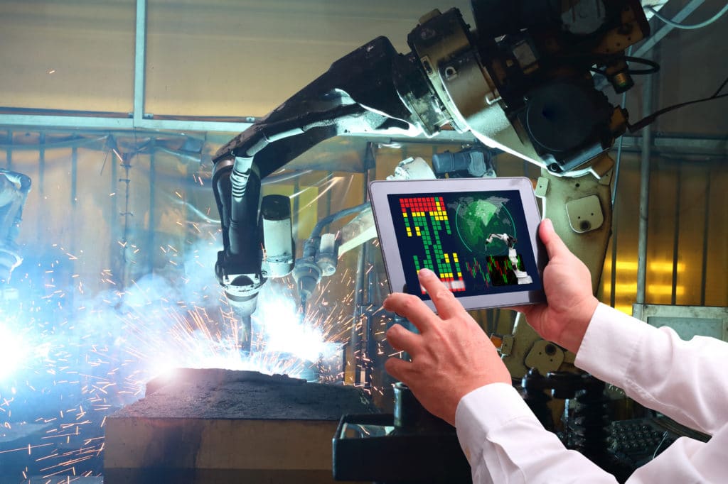 robotic welding tablet in the hands of operator with robot welding in the background