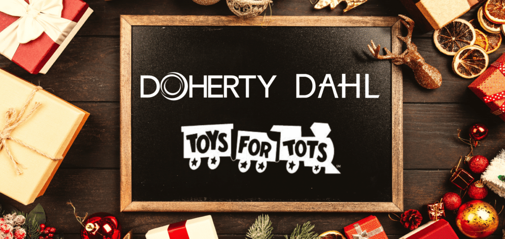 Doherty, DAHL, and Toys for Tots logos in white on chalkboard surrounded by gifts
