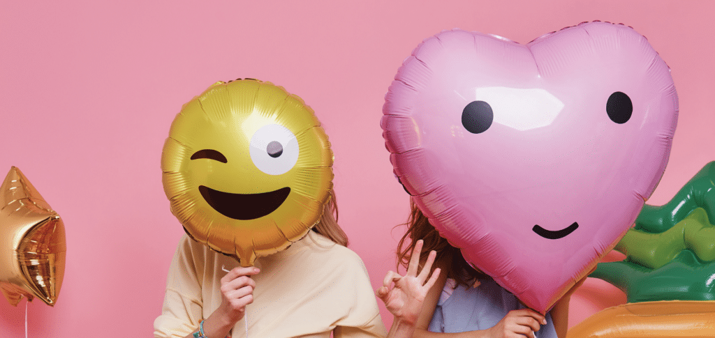 two women holding mylar balloons in front of their faces
