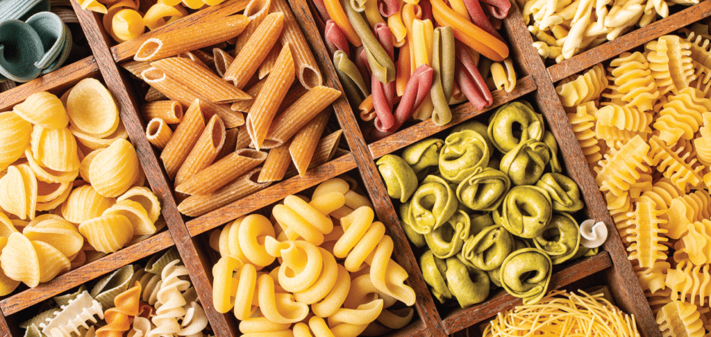 multiple dry pasta varieties in a wooden crate