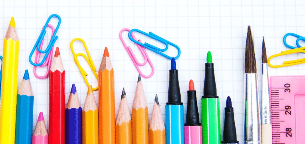 variety of pens, pencils, paper clips, and markers laid out on a white background