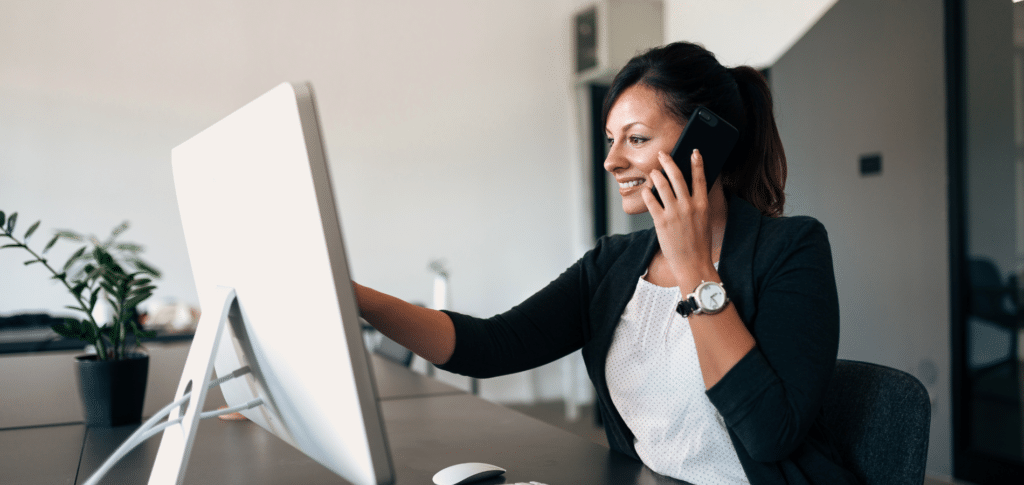 office worker talking on the phone while looking at computer screen