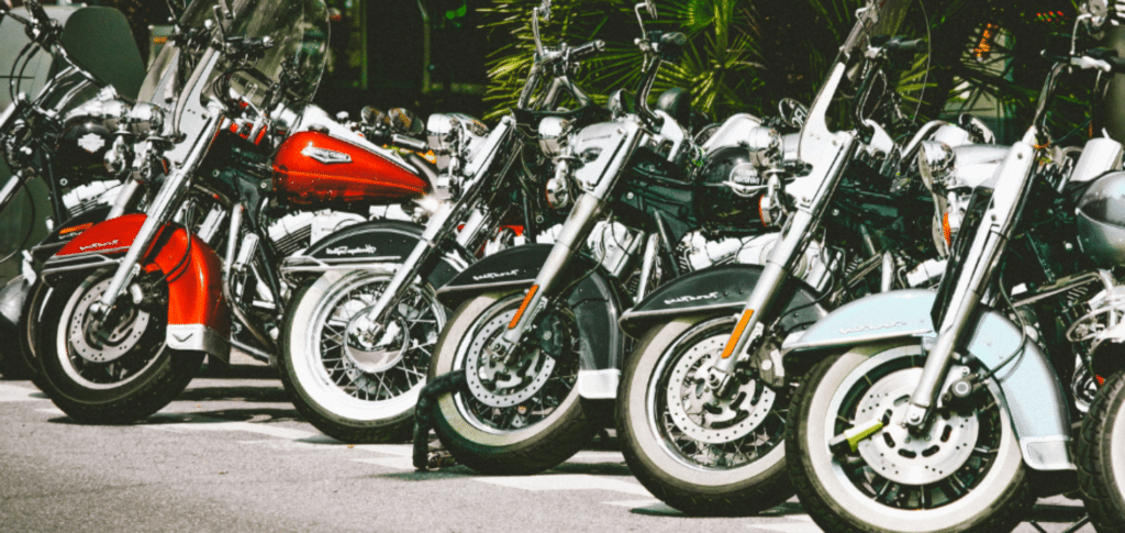 row of motorcycles parked outside in sunshine near palm trees