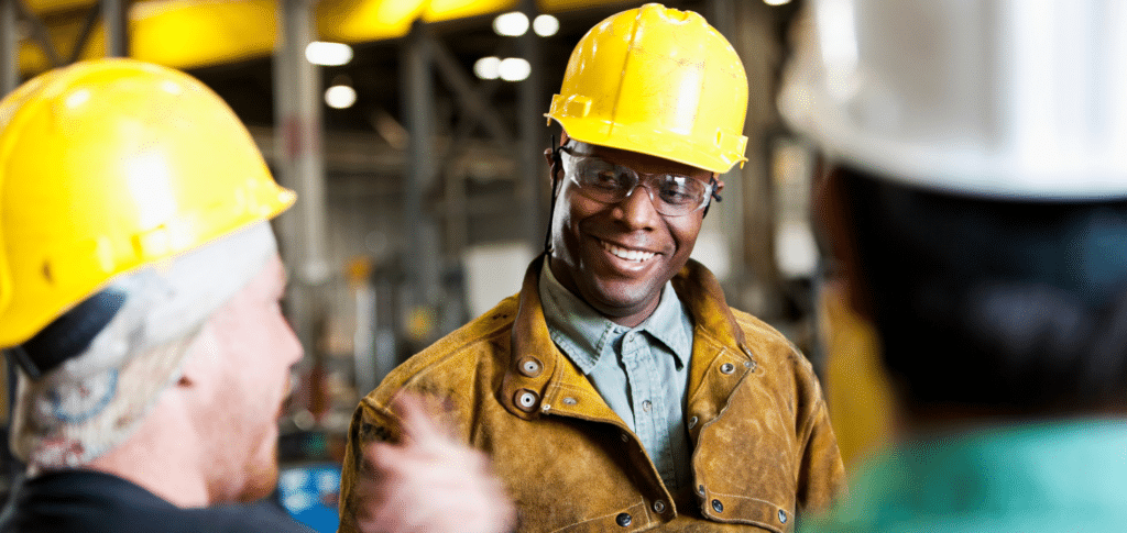 smiling manufacturing worker talking to other workers